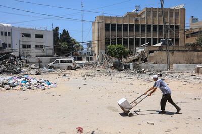A man pushes a truck trolley as he walks past the damaged headquarters of the UNRWA in Gaza city. AFP