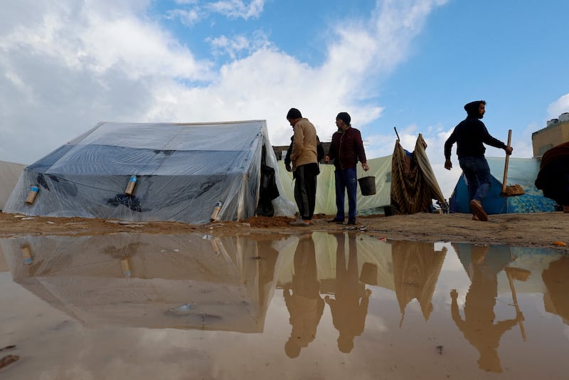 Palestinians who fled their homes amid Israeli bombardment attempt to remove water from near their tents. Reuters
