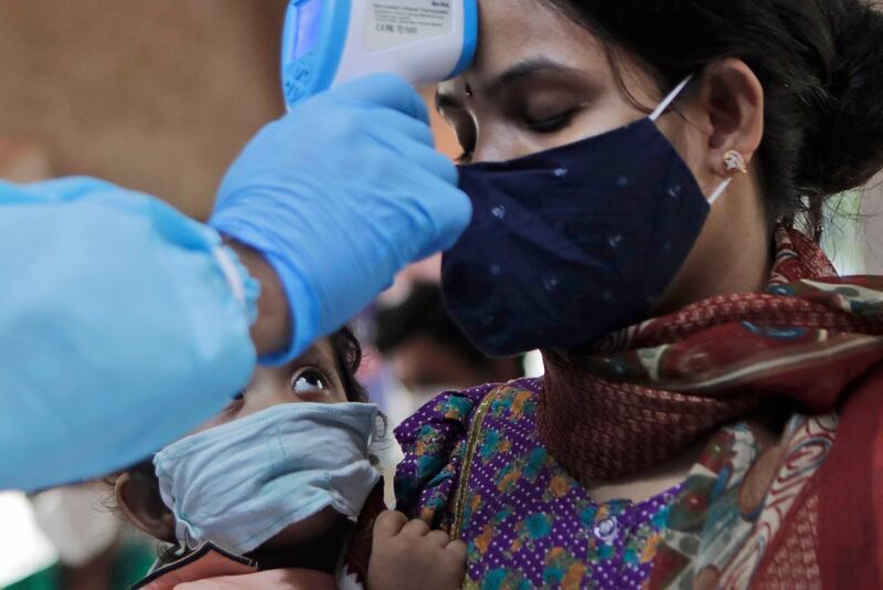 A child looks at his mother being screened for COVID-19 symptoms at an apartment complex in Mumbai, India, Tuesday, July 28, 2020. (AP Photo/Rajanish Kakade)