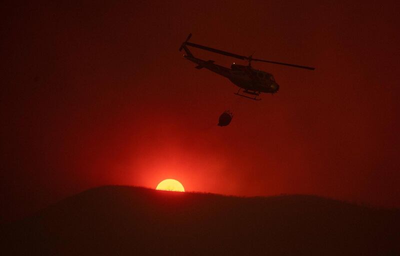 A helicopter carries water as the sun sets in the background while fighting the Mendocino Complex fire in Lakeport, California. Josh Edelson/AFP