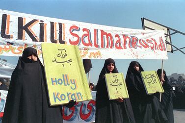 In this file photo taken on February 17, 1989, Iranian women are seen holding banners which read "Holly Koran" and "Kill Salman Rushdie" during a demonstration against British writer Salman Rushdie in Tehran.  - It has been reported that Rushdie was attacked on stage today during an event in New York.  (Photo by NORBERT SCHILLER  /  AFP)