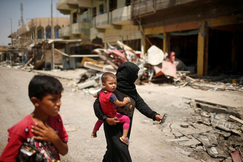 An Iraqi family walks past destroyed shops, in western Mosul, Iraq July 31, 2017. REUTERS/Suhaib Salem