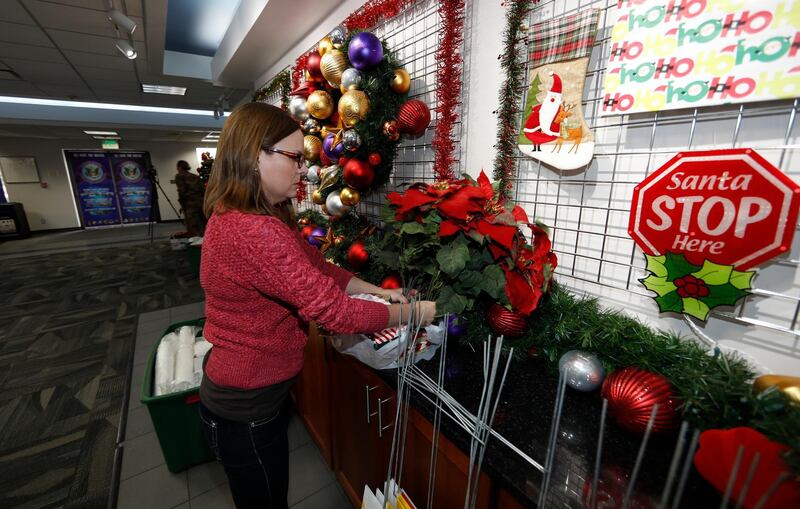 Volunteer Nicole Schreiner places a display of poinsettias in the Norad Tracks Santa centre at Peterson Air Force Base. AP