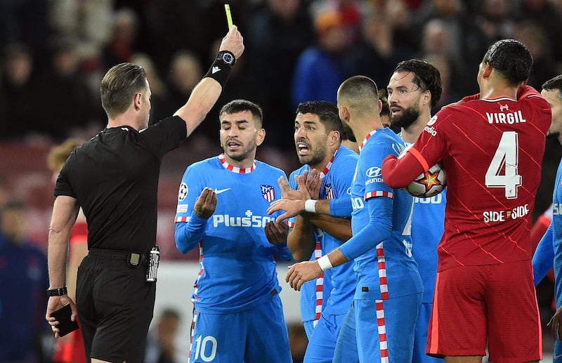 Referee Danny Makkelie shows a yellow card to Atletico Madrid's Luis Suarez after sending off his teammate Felipe. AFP