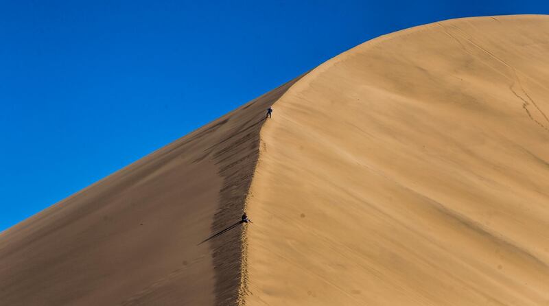 Climbers scale a dune.