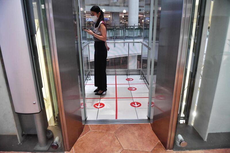 A woman stands in an elevator with markers on the floor for social distancing measures in a shopping mall in Bangkok.  AFP