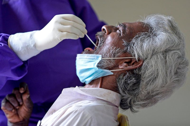 A medical worker wearing personal protective equipment collects a swab sample from a man for the coronavirus test, in Colombo. AFP