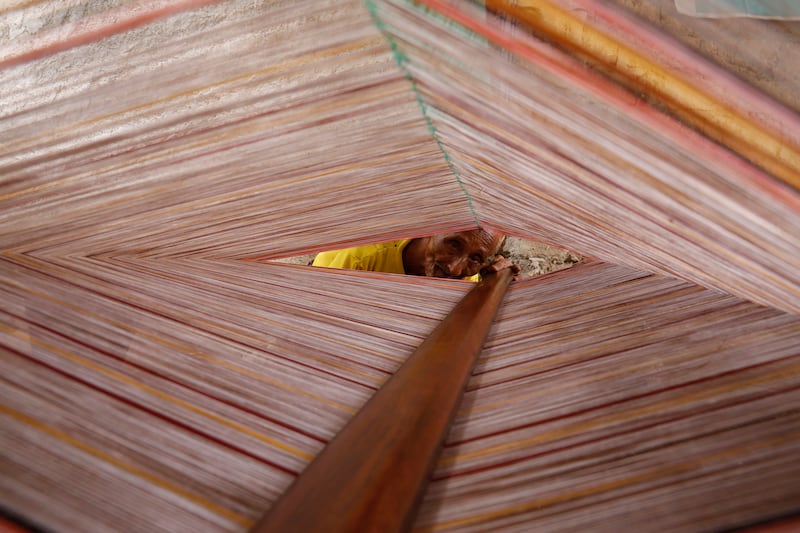 A Yemeni craftsman weaves a traditional men's fabric (known as maawaz) at a workshop in the port city of Hodeidah, Yemen, 09 February 2022 (issued 21 February 2022).  Maawaz weaving is a famous traditional Yemeni craft which is still used to product men's traditional fabric in the Arab country.  At least two craftsmen work for over 15 hours to weave manually a maawaz with harmonious decorations and colors, using a wooden loom and colorful threads.  Maawaz is a traditional Yemeni kind of wrap-around-one-piece fabric whose width is about one meter to cover the body of a man from the hips to the ankles or slightly higher.  It has been worn by Yemeni men for generations, either wrapped around itself or kept in place by a belt tight.  This woven garment is one of the most popular costumes in the coastal Yemeni regions which have hotter weather most months of the year, especially in the provinces of Hodeidah, Taiz, Aden and Hadramout, since it is very comfortable and practical.  The price of a maawaz ranges between 10,000 Yemeni rial (15 euro) for the low-quality and 65,000 rial (Approximately 100 euro) for the high quality one.   EPA / YAHYA ARHAB  ATTENTION: This Image is part of a PHOTO SET