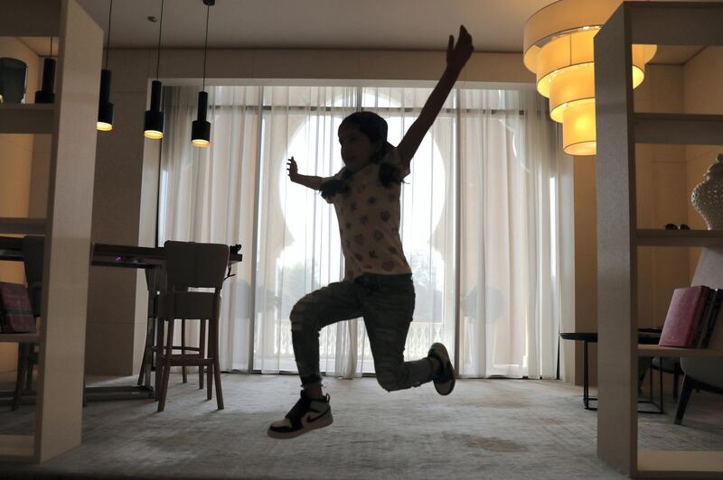 Michelle Rasul jumps around in the lobby of her apartment building in Dubai, United Arab Emirates, Sunday, May 9, 2021. Rasul, a 9-year-old girl from Azerbaijan who lives in Dubai, is scratching her way to the top as a DJ after competing in the DMC World DJ Championship. (AP Photo/Kamran Jebreili)