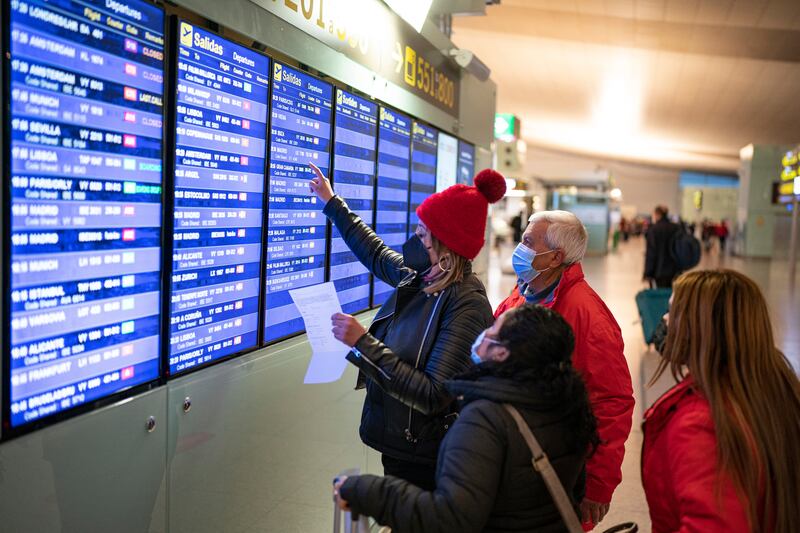 Passengers look at a flight information screen inside a terminal of the Barcelona Airport. AP