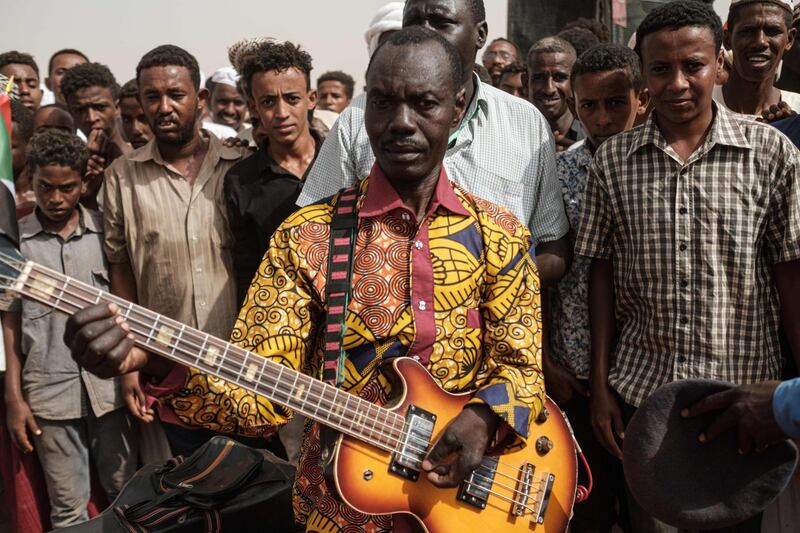 A member of traditional music and dance group plays an electric guitar before a rally for supporters of Sudan's ruling Transitional Military Council (TMC) in the village of Abraq.  AFP