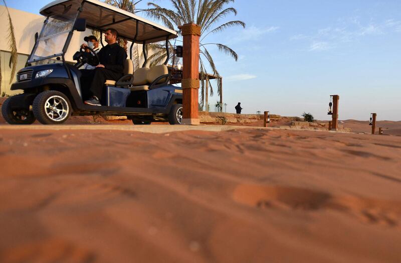 People ride in a golf cart at the "Riyadh Oasis." AFP