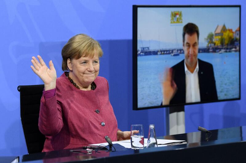 German Chancellor Angela Merkel and Bavaria's State Premier and leader of Bavaria's conservative Christian Social Union (CSU) party Markus Soeder, seen on screen via video call, wave to journalists at the end of a press conference following talks with Germany's state premiers on the current situation of the country's coronavirus vaccination campaign, at the Chancellery in Berlin. AFP