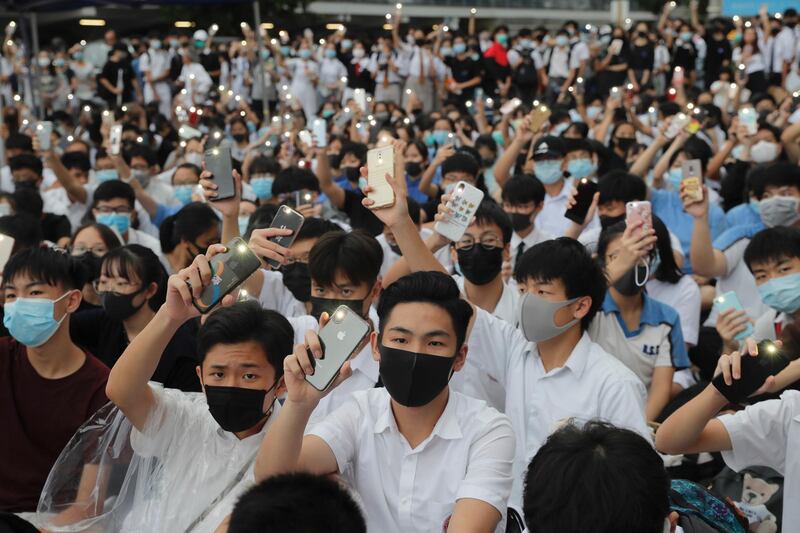Secondary school pupils hold up their smartphone lights on during a protest. AP