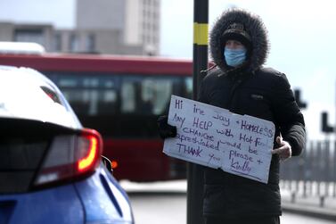 A homeless man wearing a protective face mask appeals for help to passing motorists in Birmingham. Reuters