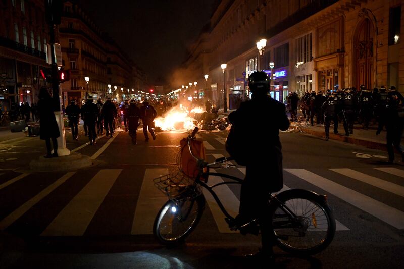 A cyclist watches a Paris protest. AFP