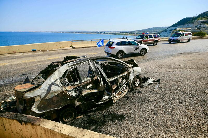 A UN peacekeeping force vehicle drives past the wreckage of a car that was targeted in Israeli strike early on Saturday near the southern Lebanese town of Naqoura. AFP