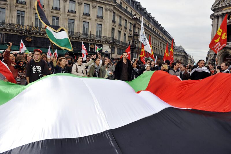 People wave a giant Palestinian flag on the square in front of the Opera on September 21, 2011 in Paris, to support Palestinian bid to seek full United Nations membership as a Palestinian state. French President Nicolas Sarkozy called today on the United Nations to admit Palestine as a non-member state, upgrading its status as simple observer but opposing a Palestinian bid for full membership.  AFP PHOTO / MEHDI FEDOUACH
 *** Local Caption ***  882050-01-08.jpg