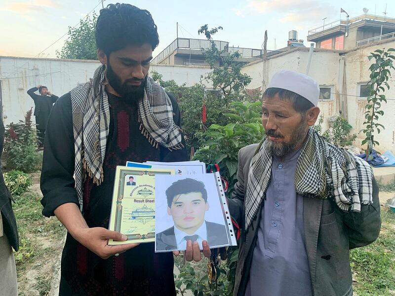 Mohammed Jan Sultani's father, Ali, right, looks at his son's Taekwondo championship certificates along with pictures of him in Kabul. Mr Sultani had clutched his national Taekwondo championship certificates as he waded through the multitudes pushing to get into Kabul airport late last week. AP