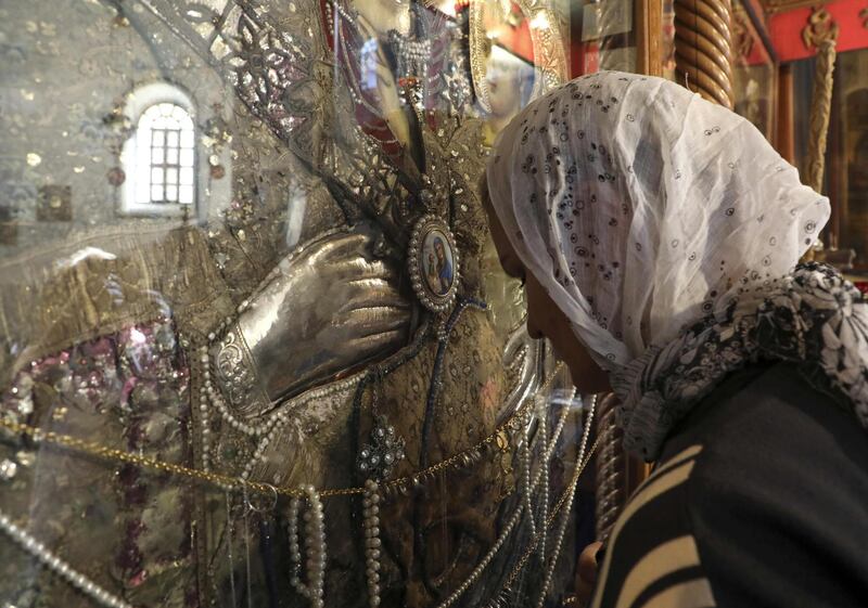 A pilgrim prays in front of an icon of the Virgin Mary at the Church of the Nativity, in the city of Bethlehem in the occupied West Bank, on December 22, 2019. Less than an hour after a group of Indian tourists arrive at Bethlehem's Church of the Nativity, they exit smiling, directly board their bus and head back to Jerusalem. The city where Christians believe Jesus was born, is teeming with tourists, but the Christmas spirit is dampened by complaints that Israeli tour operators don't allow the city to truly benefit from the influx. / AFP / HAZEM BADER
