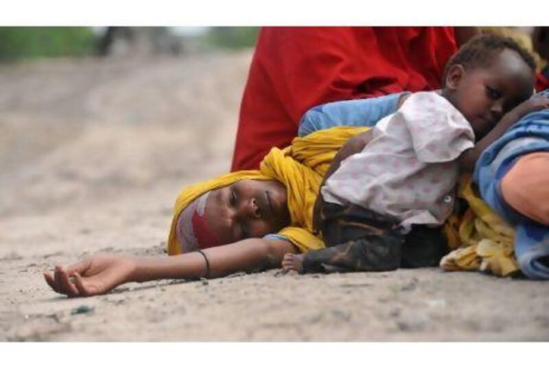 A mother lies with her child on a road in Mogadishu while waiting for assistance at a makeshift medical camp.