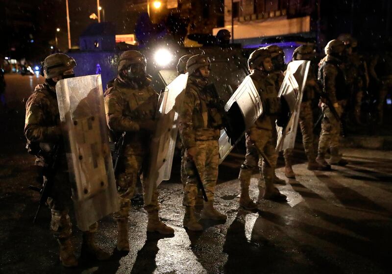 Lebanese soldiers stand under the rain as they prepare to move protesters from streets, during a protest against deteriorating living conditions and strict coronavirus lockdown measures, in Tripoli, Lebanon. AP
