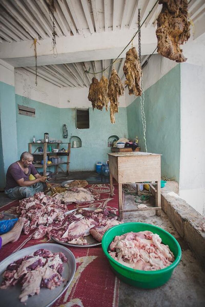 Zaher Sulaiman, son of Sulaiman Nasser, prepares meat for the Eid Al Adha feast in Misfat Al Abriyeen. Ania James for The National