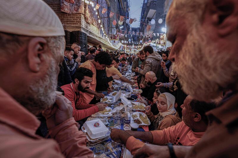 Egyptians gather in streets lined with long tables to break their Ramadan fast together