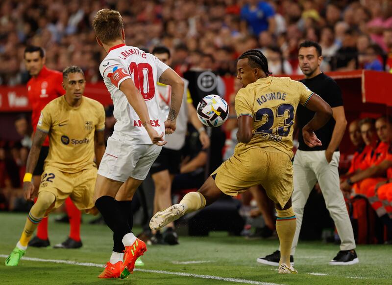 Sevilla midfielder Ivan Rakitic attempts to challenge in Barcelona's Jules Kounde. EPA