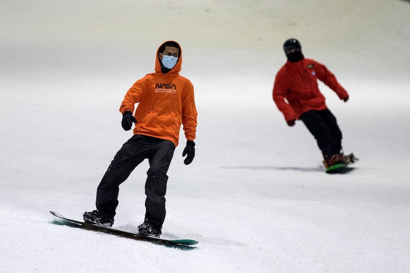 Visitors wear face masks while snowboarding at Ski Dubai, which reopened on May 27 along with cinemas, gyms and other entertainment venues. Mahmoud Khaled / EPA