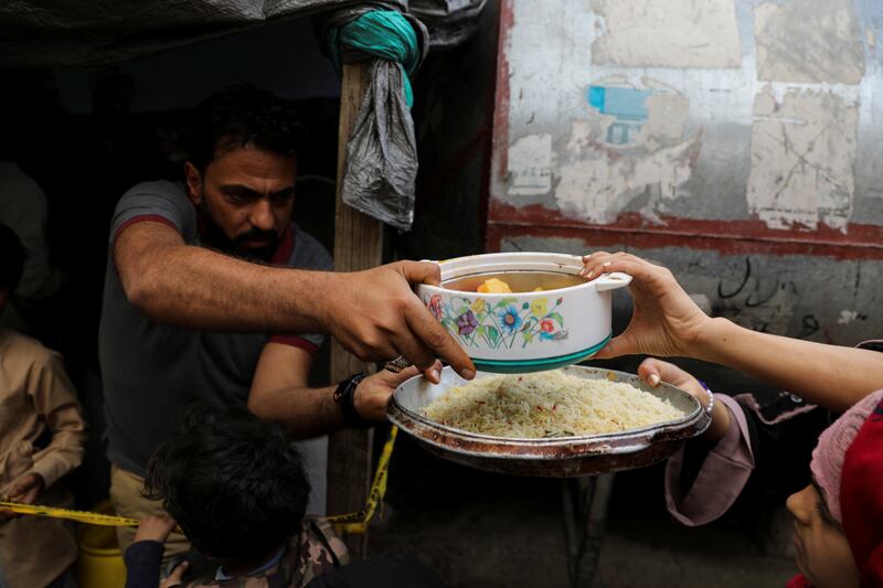 A volunteer gives a meal to a woman at a charity kitchen in Sanaa.