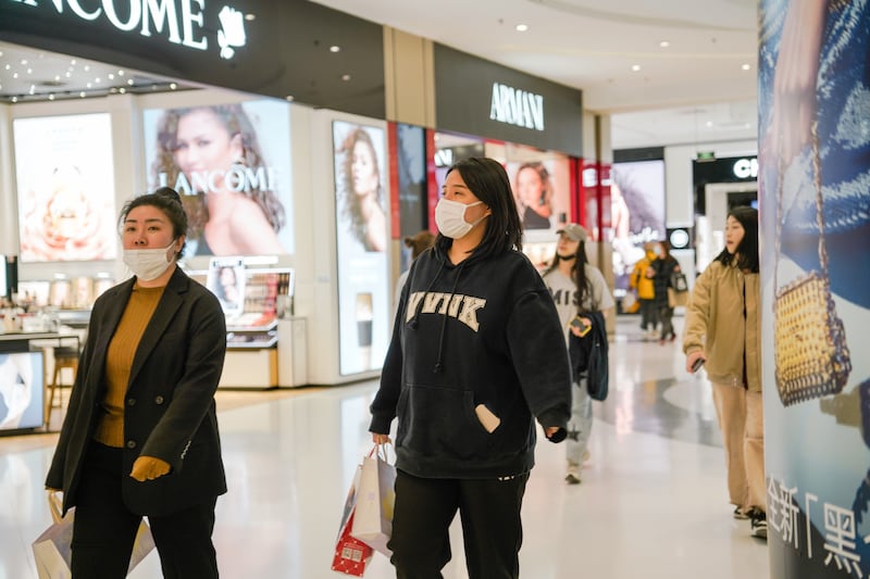 People wearing face masks walk in a shopping mall in Beijing. Chinese consumers, at home and abroad, represented about a third of total personal luxury goods spending before Covid-19.  EPA