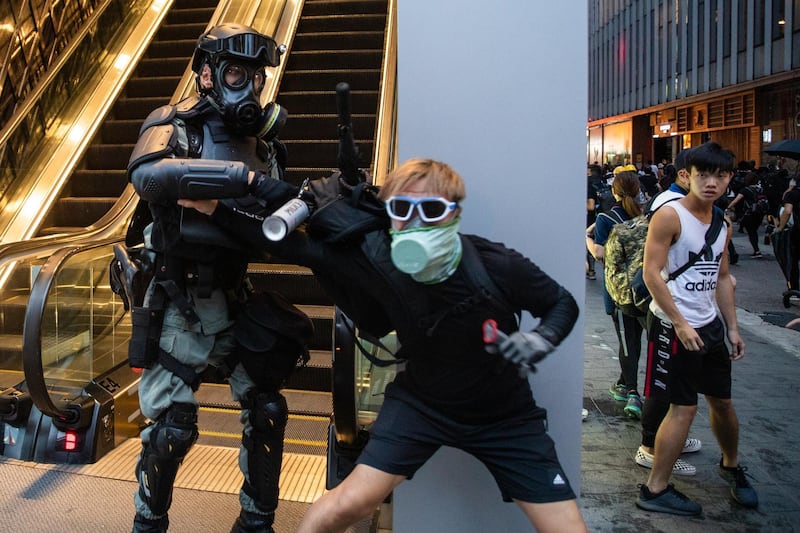 A riot police officer detains a demonstrator wearing a face mask during a protest in Admiralty district of Hong Kong. Bloomberg