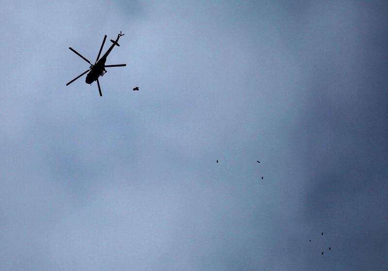 A picture taken on February 20, 2018 shows a Russian-made Syrian army attack helicopter dropping a payload over the rebel-held town of Arbin, in the besieged Eastern Ghouta region on the outskirts of the capital Damascus. / AFP PHOTO / Amer ALMOHIBANY
