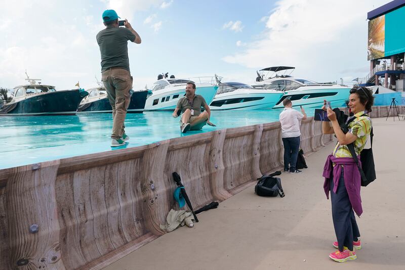 Members of the racing media take photos on the painted surface simulating water near dry-docked yachts outside Hard Rock Stadium.