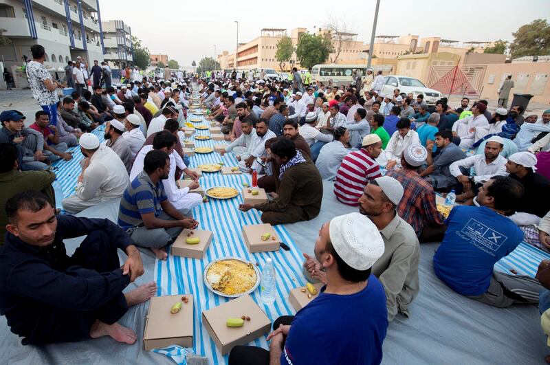 DUBAI, UNITED ARAB EMIRATES -  Workers waiting for the sundown to break their fast.  Dubai Police join hands with Berkeley Assets to serve up Iftar dinner to mark Laylatul Qadr for 10,000 labourers with seating for 5,000 and another 5,000 laborers will go home with meal boxes in Al Muhaisnah, Dubai.  Ruel Pableo for The National