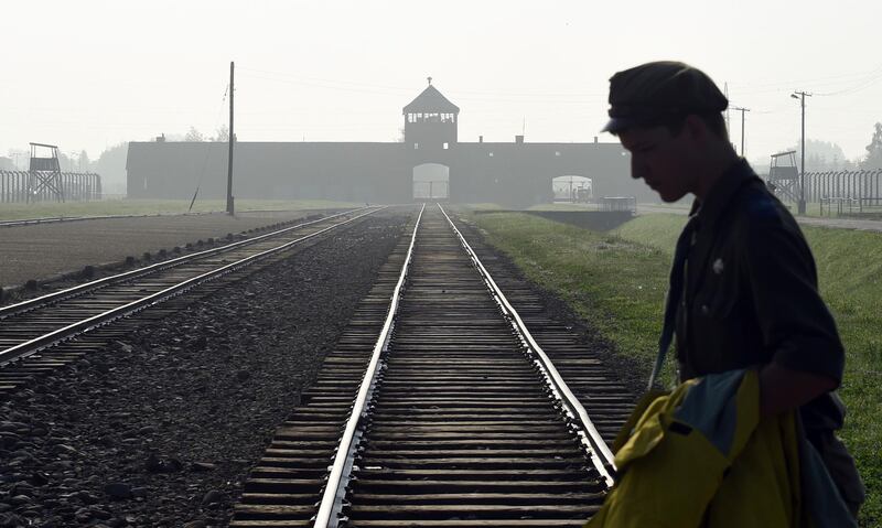 FILE - In this July 29, 2016 file photo a man crosses the iconic rails leading to the former Nazi death camp of Auschwitz-Birkenau prior to a visit by Pope Francis, in Poland. The office of Polish President Andrzej Duda said the leader will on Tuesday, Feb. 6, 2018 announce his decision on whether to sign legislation penalizing certain statements about the Holocaust. (AP Photo/Alik Keplicz, file)