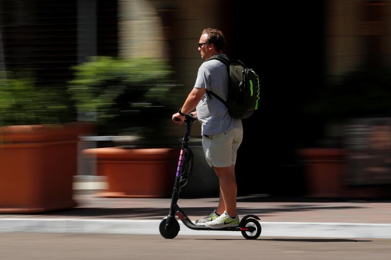 A man travels along a street atop an electric scooter in downtown San Diego, California, U.S., July 29, 2019. Picture taken July 29, 2019. REUTERS/Mike Blake