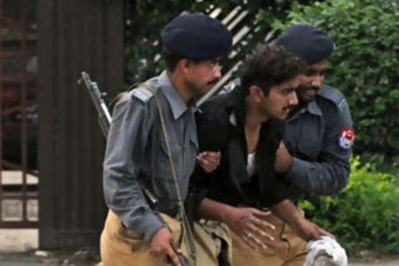 Pakistani policemen help an injured colleague after a suicide attack near the Red Mosque.