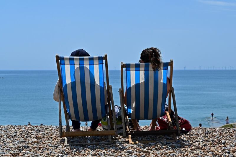 People sit in deckchairs as they enjoy the sunshine on the beach in Brighton on the south coast of England following a further relaxation of the novel coronavirus COVID-19 lockdown rules.   AFP