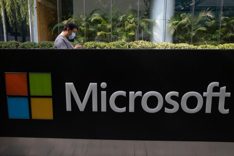 FILE - A man wearing a mask looks at this phone outside the Microsoft office in Beijing, China in a Friday, Aug. 7, 2020 file photo. Microsoft is buying the company behind popular video games The Elder Scrolls, Doom and Fallout. The software giant said Monday, Sept. 21, 2020 that it is paying $7.5 billion for ZeniMax Media, the parent company of video game publisher Bethesda Softworks.  (AP Photo/Ng Han Guan, File)