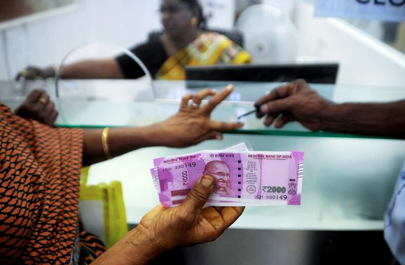 An Indian woman holds 2000 INR notes as she has her finger marked with indelible ink after exchanging 500 and 1000 INR banknotes at a bank in Chennai AFP / ARUN SANKAR