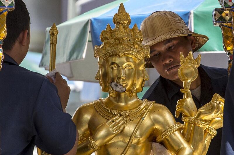 Workers clean a statue of Hindu god Brahma. Throngs of tourists come there to pray at all hours, lighting incense and offering flowers purchased from rows of stalls set up on the pavement along the shrine. Athit Perawongmetha / Reuters
