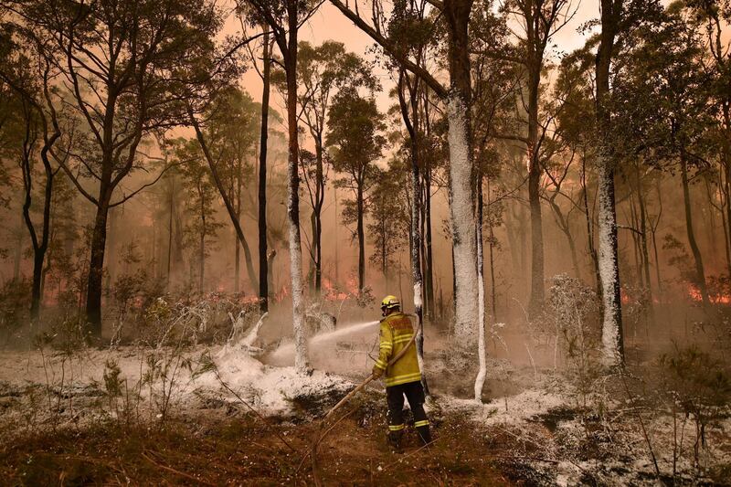(FILES) In this file photo taken on January 01, 2020 A firefighter sprays foam retardant on a back burn ahead of a fire front in the New South Wales town of Jerrawangala on January 1, 2020. - A major operation to reach thousands of people stranded in fire-ravaged seaside towns was under way in Australia on January 1 after deadly bushfires ripped through popular tourist spots and rural areas leaving at least eight people dead. (Photo by PETER PARKS / AFP)