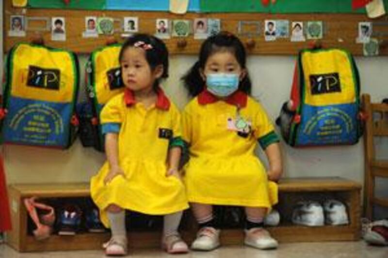 A masked girl sits with a classmate at a kindergarten in Hong Kong on June 11 2009.