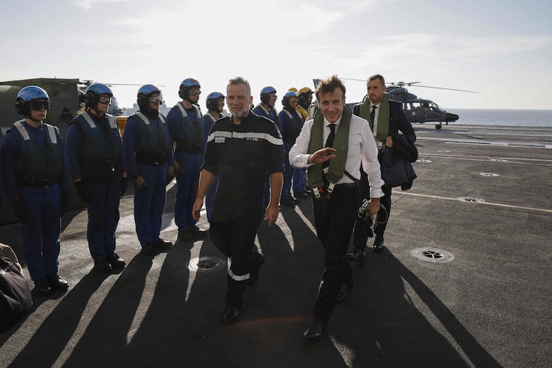 Mr Macron, front right, lands on the carrier before attending a regional conference in Jordan 