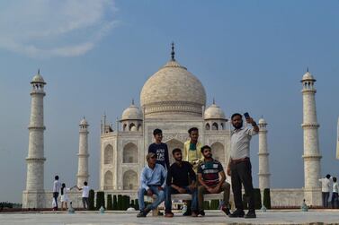 A group of Indian tourists pose for photographs in front of the Taj Mahal monument after it was reopened on Monday. AP
