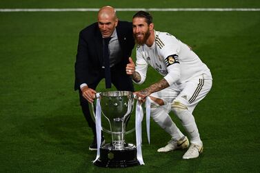 Real Madrid's French coach Zinedine Zidane (K) and Real Madrid's Spanish defender Sergio Ramos celebrate with the trophy after winning the Ligs title after the Spanish League football match between Real Madrid CF and Villarreal CF at the Alfredo di Stefano stadium in Valdebebas, on the outskirts of Madrid, on July 16, 2020. / AFP / GABRIEL BOUYS