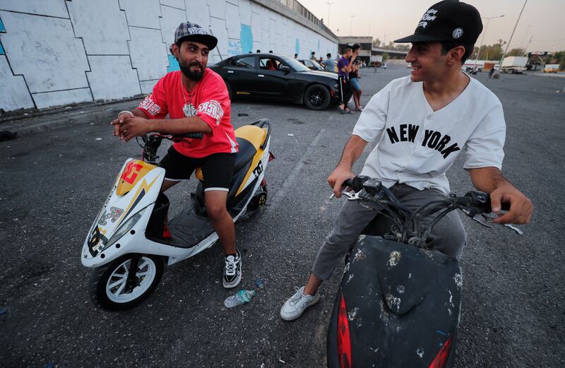 Young Iraqis chat as they gather to perform stunts on motorbikes and scooters in the Jadriya district of Baghdad. About 42 per cent of young Iraqis say religion is central to their identity. Photo: Ahmad Al Rubaye / AFP