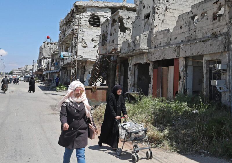 Syrians walk past buildings heavily damaged during Syria's civil war, in the central city of Homs. AFP